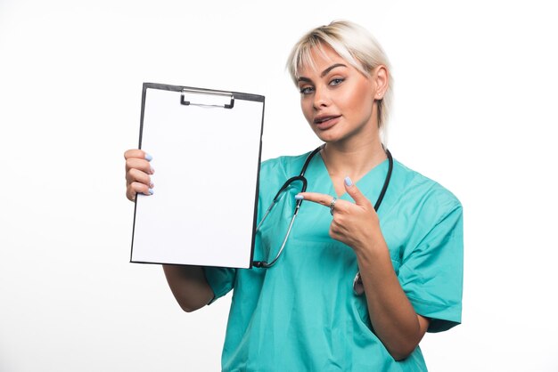 Photo gratuite femme médecin tenant un presse-papiers doigt pointé sur le mur blanc.