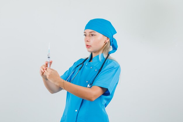 Femme médecin tenant une seringue pour injection en uniforme bleu