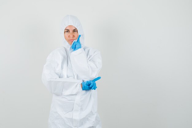 Femme médecin en tenue de protection, gants debout dans la pensée pose et à la recherche sensible