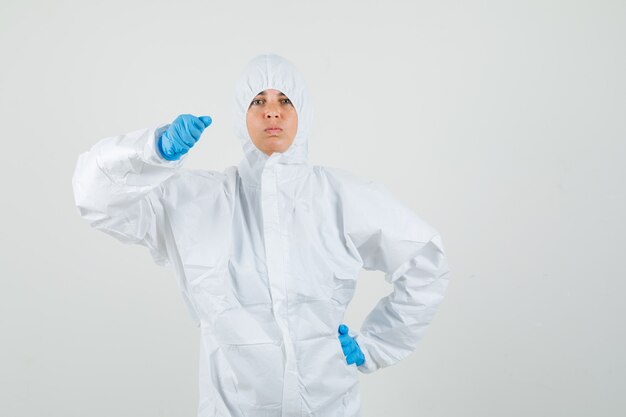 Femme médecin en tenue de protection, gants menaçant avec le poing et à la stricte