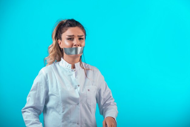 Femme médecin en uniforme blanc couvrant sa bouche et pleurant.