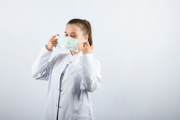 Femme médecin en uniforme blanc portant un masque médical