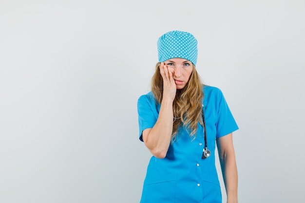 Femme médecin en uniforme bleu ayant mal aux dents et à la maladie