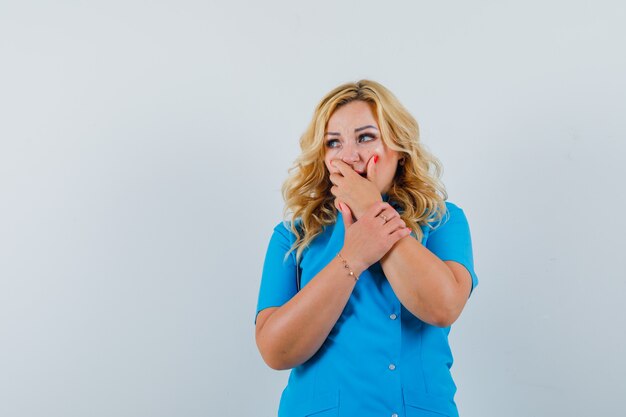 Femme médecin en uniforme bleu à l'écart avec la main sur la bouche et à l'espace terrifié pour le texte
