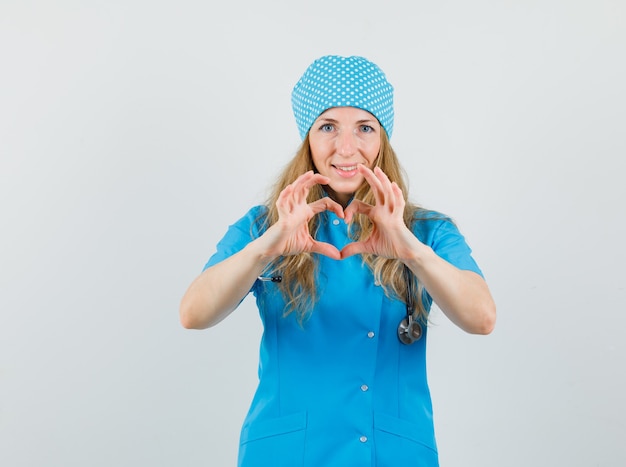 Femme médecin en uniforme bleu montrant le geste du cœur et à la joyeuse
