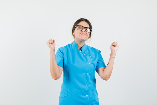 Femme médecin en uniforme bleu montrant le geste du vainqueur et l'air paisible