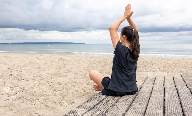 Une femme médite assise au bord de la mer