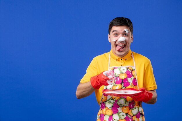 Femme de ménage joyeuse vue de face avec de la mousse sur son assiette de lavage du visage sur un espace bleu