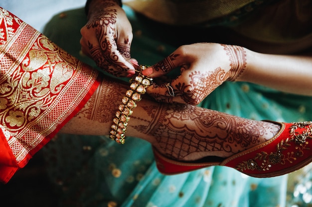 Femme met le bracelet sur la jambe de la mariée hindoue