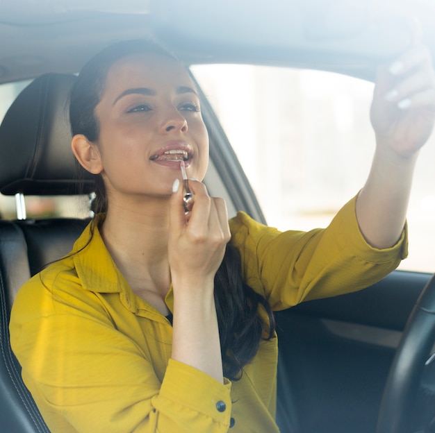 Photo gratuite femme met du rouge à lèvres et assis dans la voiture