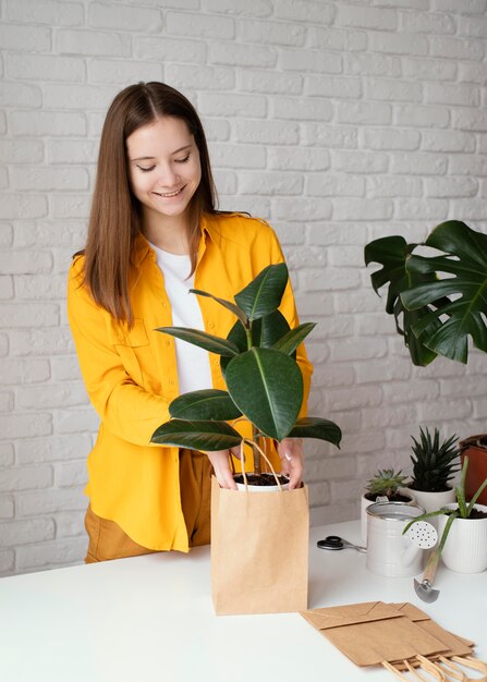 Une femme met une plante dans un sac en papier.