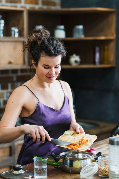 Femme mettant des carottes coupées dans une casserole