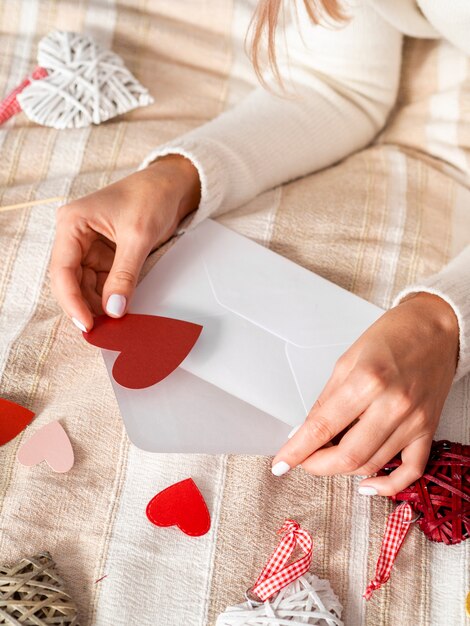 Femme mettant des coeurs dans une enveloppe