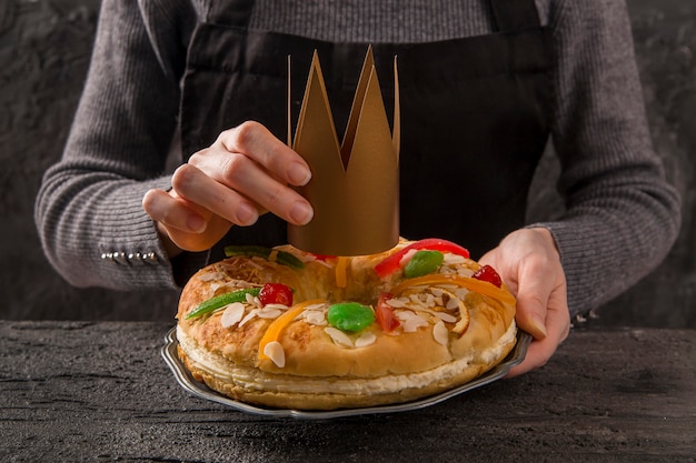 Femme mettant une couronne sur le dessert heureuse épiphanie