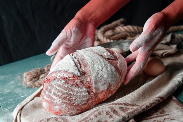 Femme mettant du pain fait maison entier avec les mains sur la serviette brune. farine sur le pain.