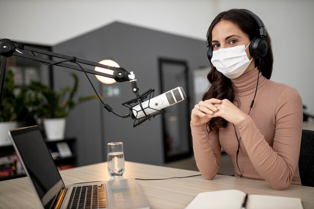 Femme avec microphone et masque médical dans un studio de radio