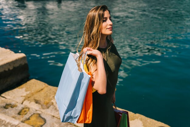 Femme mignonne près de la mer après le shopping