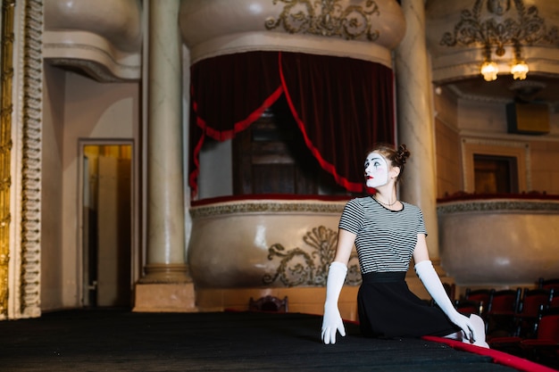 Femme mime artiste assis au bord de la scène dans l&#39;auditorium