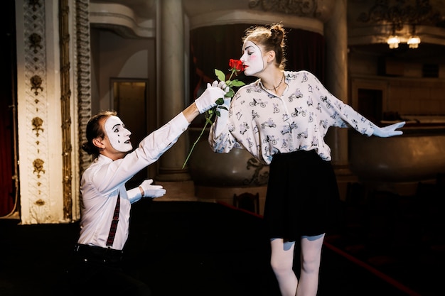 Femme mime artiste sentant la rose rouge donnée par le mime masculin sur scène