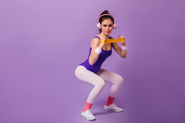 Femme mince impliquée dans le sport sur un mur violet