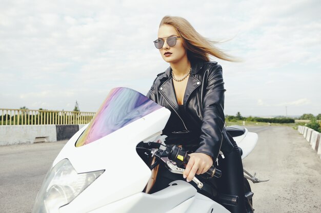 Femme à la mode au volant d'un vélo sur une route