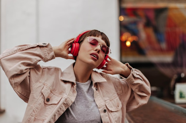 Femme à la mode avec un casque rouge écoutant de la musique à l'extérieur