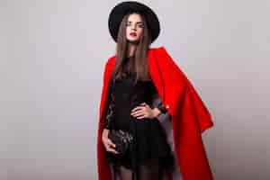 Photo gratuite femme à la mode en manteau rouge et chapeau noir posant