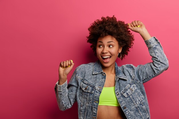 Une femme à la mode à la peau foncée ravie porte un haut et une veste en jean