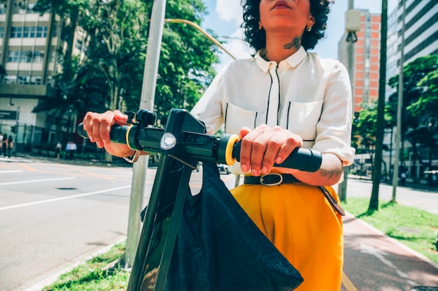 Photo gratuite femme moderne dans une ville avec un scooter électrique