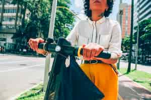 Photo gratuite femme moderne dans une ville avec un scooter électrique