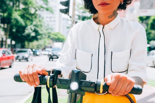 Photo gratuite femme moderne dans une ville avec un scooter électrique