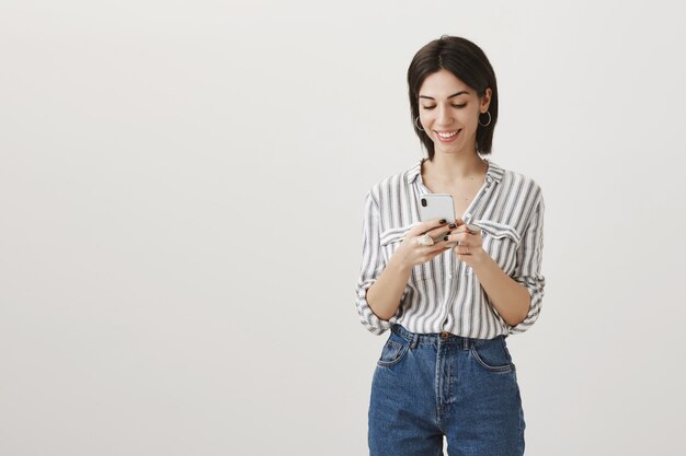 Femme moderne élégante à l'aide de téléphone mobile, regardant smartphone avec sourire heureux