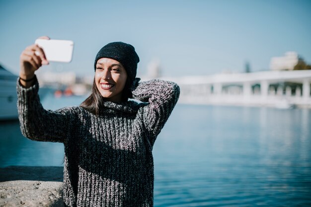 Femme moderne prenant selfie avec de l&#39;eau en arrière-plan