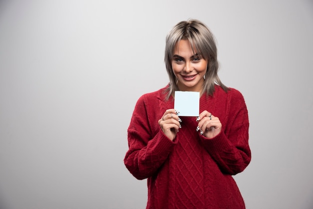 Femme montrant le bloc-notes sur fond gris.