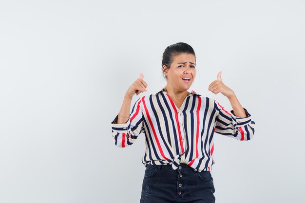 femme montrant deux pouces vers le haut en chemise, jupe et à la confiance.