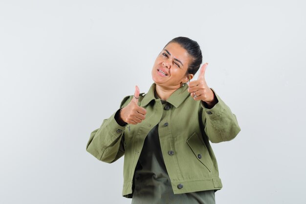 femme montrant deux pouces vers le haut en veste, t-shirt et à la confiance