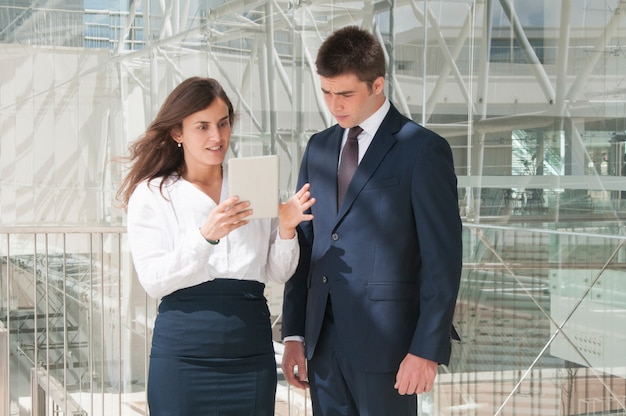Photo gratuite femme montrant des données sur un homme sur une tablette, femme semblant étonnée