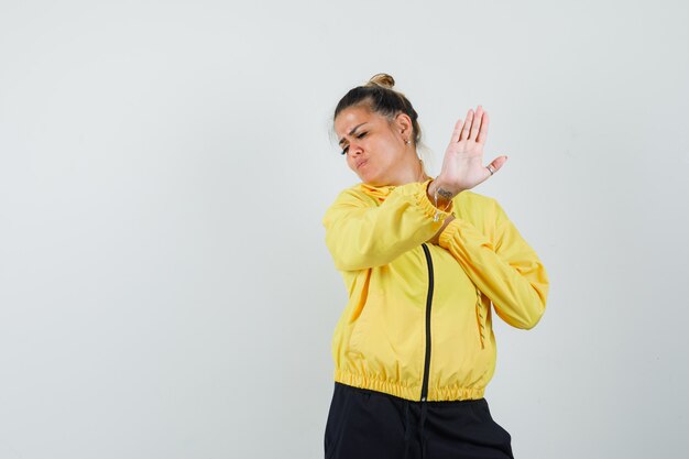 Femme montrant le geste d'arrêt en costume de sport et à l'ennui. vue de face.