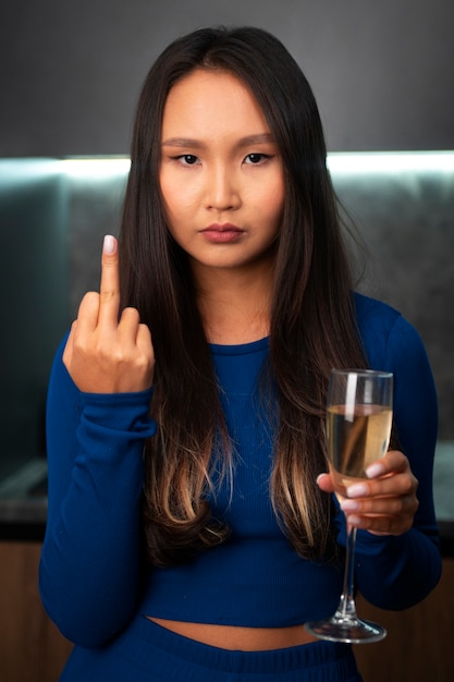 Photo gratuite femme montrant le majeur dans la cuisine en buvant du champagne