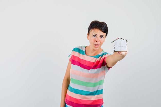 Femme montrant le modèle de maison en t-shirt rayé et à la préoccupation