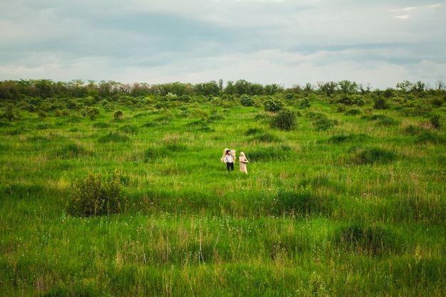 femme en mouchoir et homme marchant dans le pré