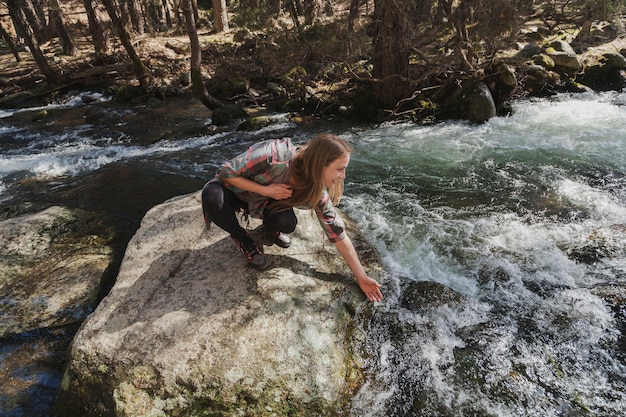 Femme mouillant sa main dans la rivière