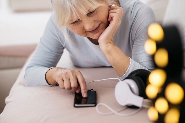 Femme mûre à l&#39;aide de smartphone sur le canapé