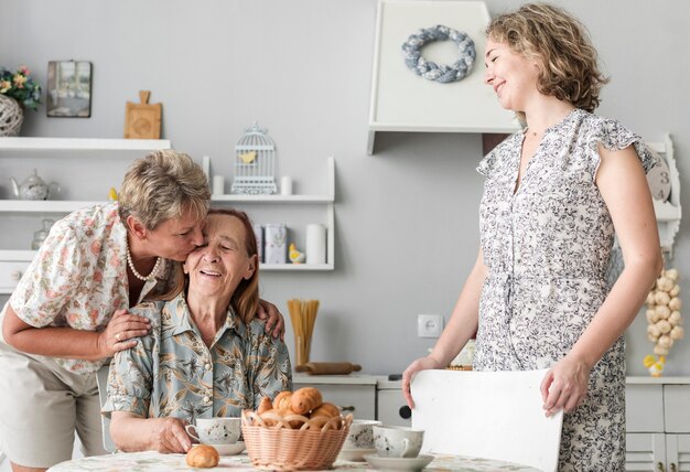 Femme mûre embrasse sa mère âgée dans la cuisine