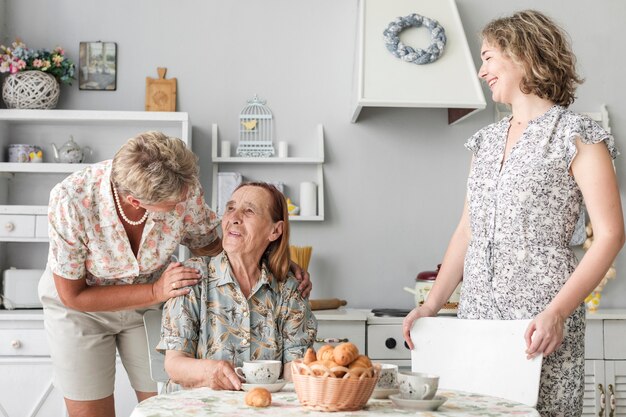 Femme mûre parle avec sa mère assise sur une chaise devant sa fille