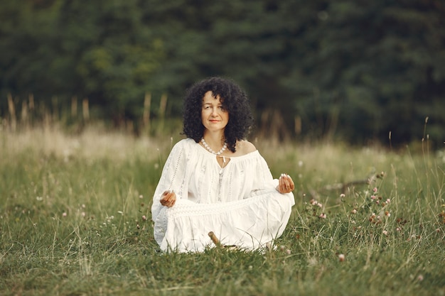 Photo gratuite femme mûre pratiquant le yoga sur le pré seul