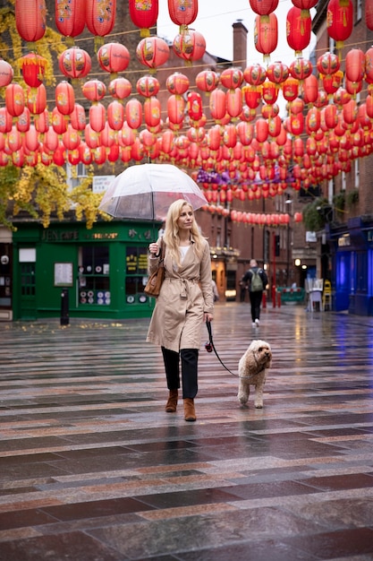 Photo gratuite femme mûre promenant son chien dans les rues de la ville pendant qu'il pleut