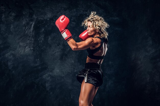 Une femme musclée sportive fait la démonstration de ses exercices de boxe, portant des gants.