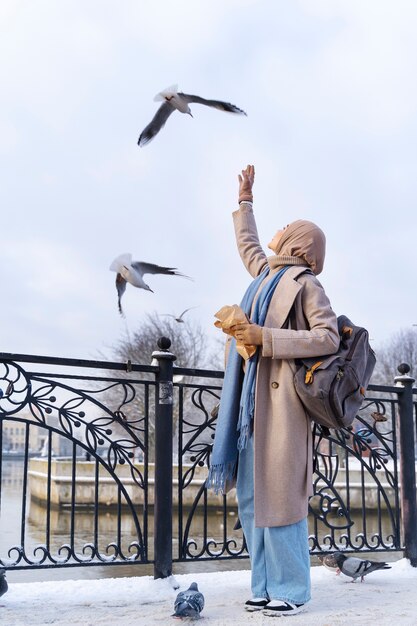 Femme musulmane nourrissant les pigeons lors d'un voyage dans la ville