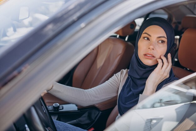 Femme musulmane parlant au téléphone dans sa voiture